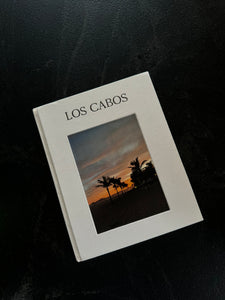 Libro con portada blanca y fotografía, en superficie negra